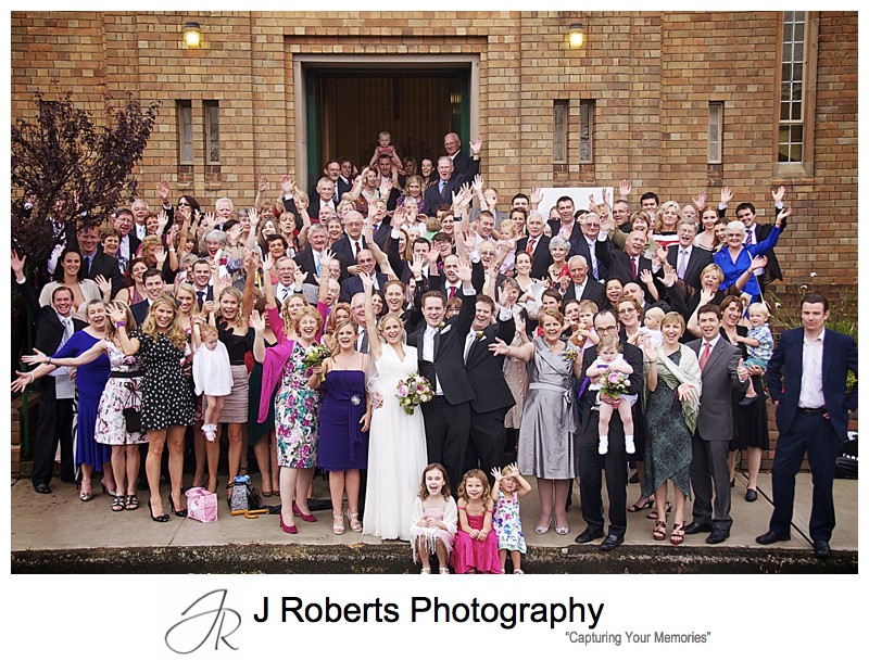 Whole group photo cheering after wedding ceremony - wedding photography sydney